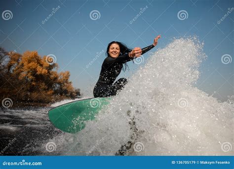Fille De Brune Sautant Sur Le Wakeboard Vert Sur Les Genoux De Recourbement Image Stock Image
