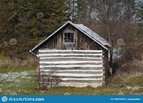 Old Log Cabin Storage Building In The Woods In Early Winter Light Snow