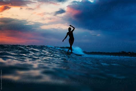 Silhouette Of Woman In The Ocean Surfing Wave At Sunset Beautiful