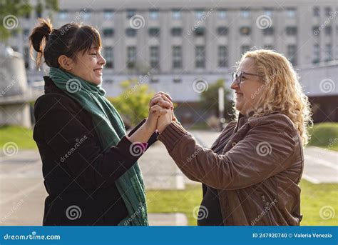 Portrait Of A Smiling Lesbian Couple Holding Hands And Looking To Each Other And Looking To Each
