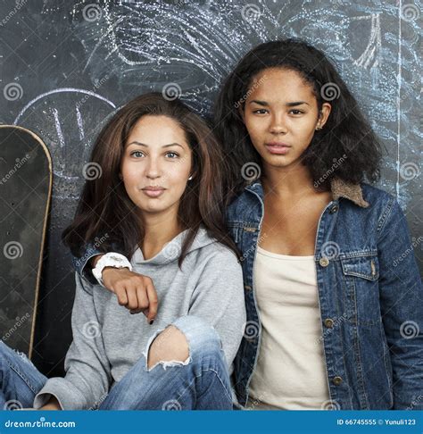 two mulatto girlfriends teenage in classroom hugging at blackboard back to school concept stock