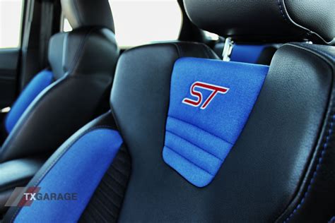 The Interior Of A Car With Blue Leather Seats And St Logo On The Front Seat