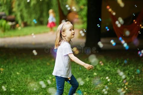 Happy Adorable Preschooler Girl Playing With Bubbles Outdoors On A