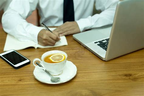 Businesswoman Hand Writing Note With Cup Of Lemon Tea And Notebook