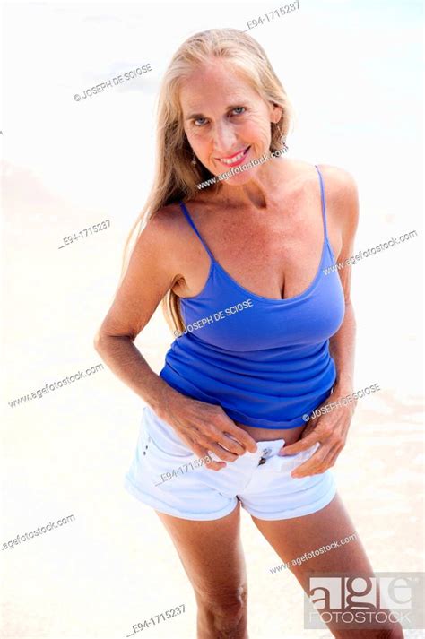 Portrait Of A 57 Year Old Woman On A Beach Smiling At The Camera Stock