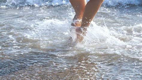Tanned Female Legs On Beach Water Splashing On Feet In Ocean On Sandy