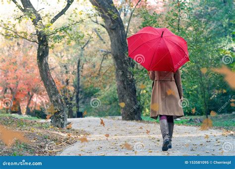 Woman With Red Umbrella Walking At The Rain In Beautiful Autumn Park