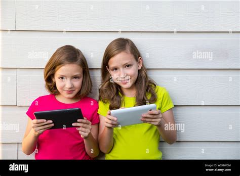 Twin Sister Girls Playing With Tablet Pc Happy On White Wall Looking