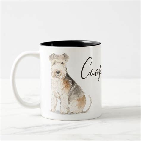 A White And Brown Dog Sitting On Top Of A Table Next To A Coffee Mug