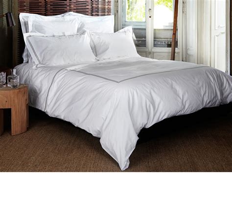 A Bed With White Sheets And Pillows In A Room