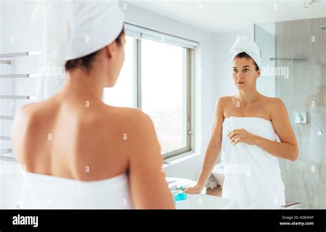 Woman Standing In Front Of Mirror In Bathroom Woman In Towels Wrapped Around Head And Body