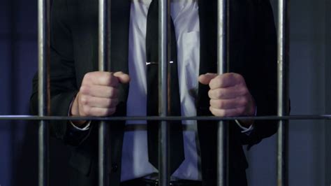 White Collar Crime Zoom Out From Hands On Prison Bars Stock Video