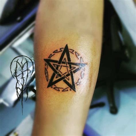A Person With A Tattoo On Their Arm Has A Pentagramil In The Shape Of A Star