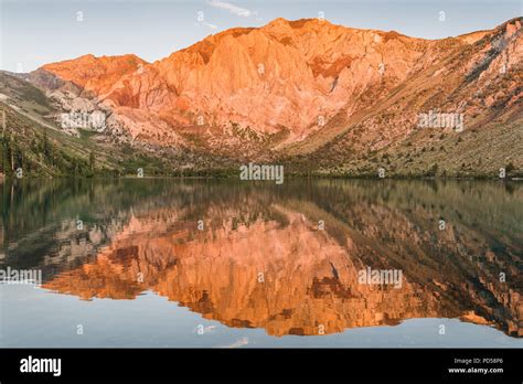 Sunrise Casts Golden Light On Mountain Peaks Reflected In The Calm
