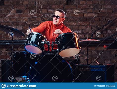 Stylish Musician In Sunglasses Sits Behind The Drum Set Against A Brick Wall Perform In Night
