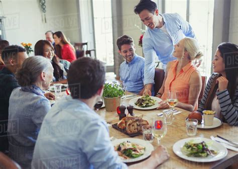 Waiter Serving Food To Friends Dining At Restaurant Table Stock Photo
