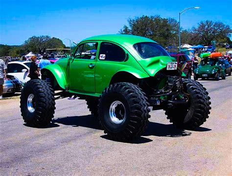 A Green Monster Truck Driving Down A Street Next To Other Cars And