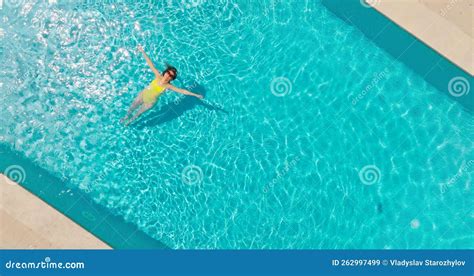 Top Down View Of A Woman In An Yellow Swimsuit Lying On Her Back In The Pool Stock Video