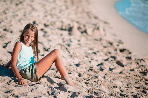 Petite Fille Sur La Plage Joue Avec Du Sable Au Coucher Du Soleil Photo Premium