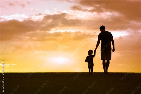 Silhouette Of Loving Father Walking Side By Side With Son Holding Hands