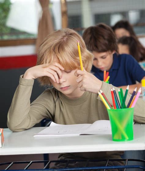Bored Schoolboy Sitting At Desk In Classroom Royalty Free Stock Image