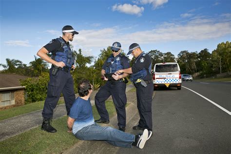 Three Police Officers Standing Over A Man Laying On The Ground