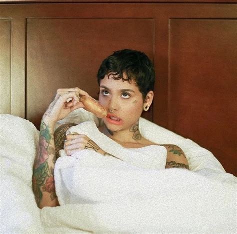 A Woman Laying In Bed Covered By A Blanket With Tattoos On Her Arms And Chest