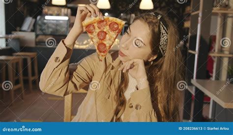 A Tender Young Girl Blonde Eats Pizza In A City Cafe And With A Smile