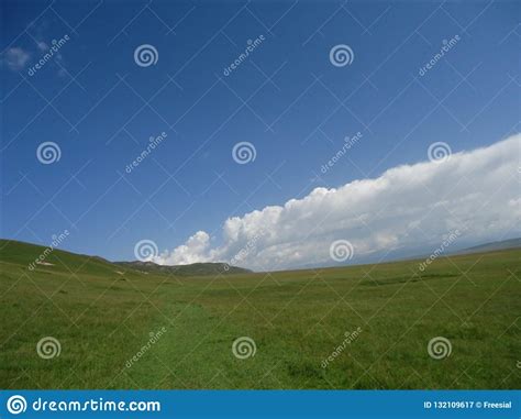 White Clouds Blue Skies Green Meadows And Mountains Stock Image