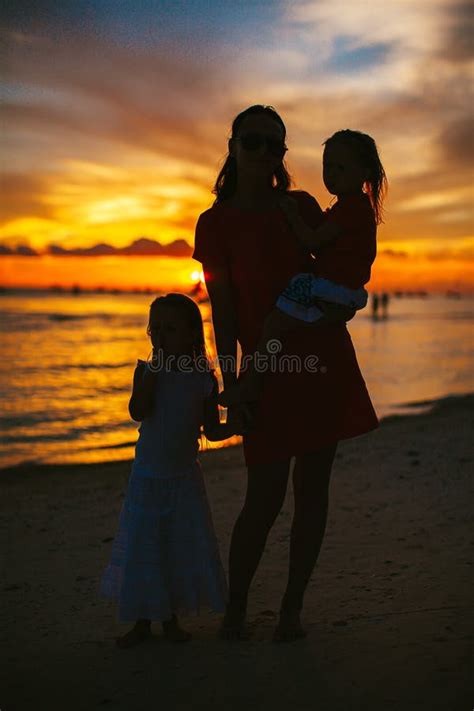Beautiful Mother And Daughter On The Beach Enjoy Sunset View Stock