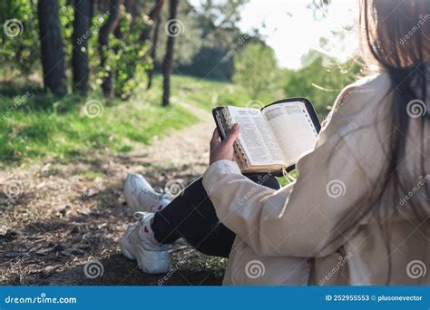 christian woman holds bible in her hands reading the bible in nature concept for faith