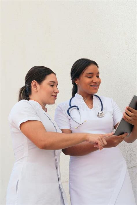 Two Female Nurses Discussing While Looking At Digital Tablet Stock