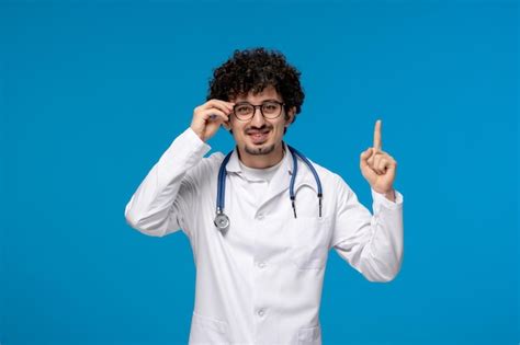 Premium Photo Doctors Day Curly Brunette Cute Guy In Medical Uniform Wearing Glasses And Smiling