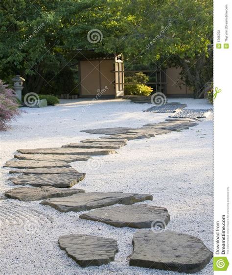 A Stone Path In The Middle Of A Graveled Area With Trees And Bushes