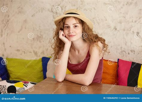 Indoor Image Of Attractive Positive Female Sitting On Sofa Putting Her Arms On Table Touching