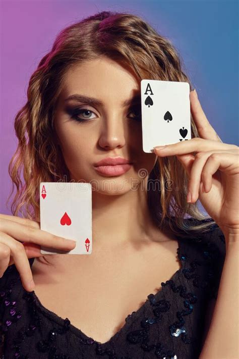 Brown Haired Lady In Black Shiny Dress Holding Two Playing Cardsnear Her Face Posing On