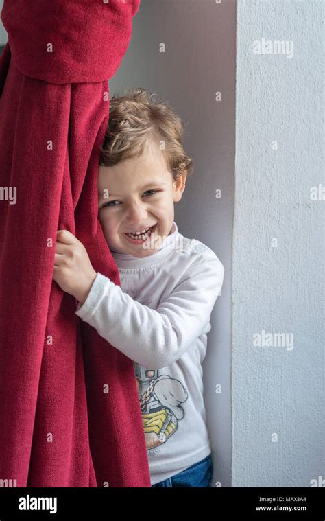 Child Hiding Behind A Red Curtain With Smiling Gesture Stock Photo Alamy