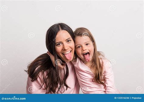 A Small Girl And Her Mother Sticking Tongues Out In A Studio Royalty