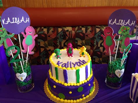 There Is A Birthday Cake On The Table With Purple And Green Decorations