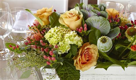 A longer floral arrangement with a base of succulents leading up into a vase of white rosebuds. Summer Floral Arrangements Ideas for Home with Orange Flowers