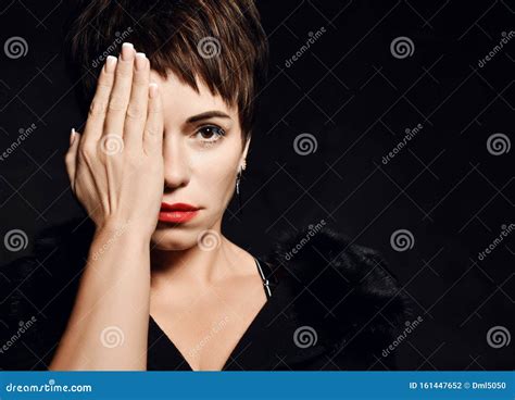 Portrait Of Severe Woman Covering Half Of Her Face With Her Hand Hiding On Dark Background