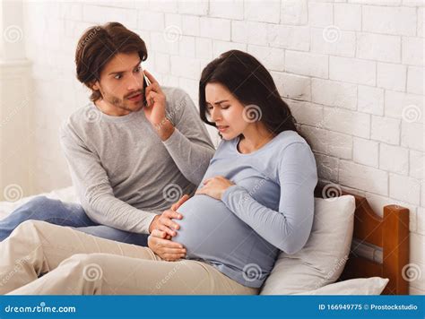 worried husband calling doctor for his pregnant wife having contractions royalty free stock