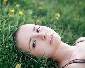 A Girl With A Shaved Head And Red Bushes In The Background Stocksy United