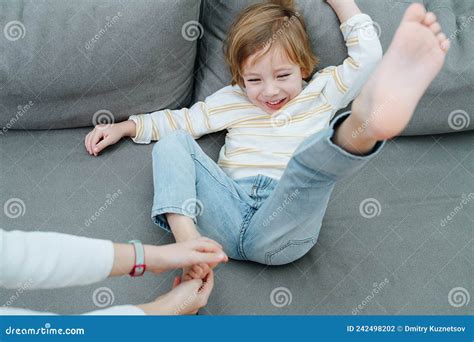 Squirming Laughing Boy Being Foot Tickled On The Couch Stock Photo