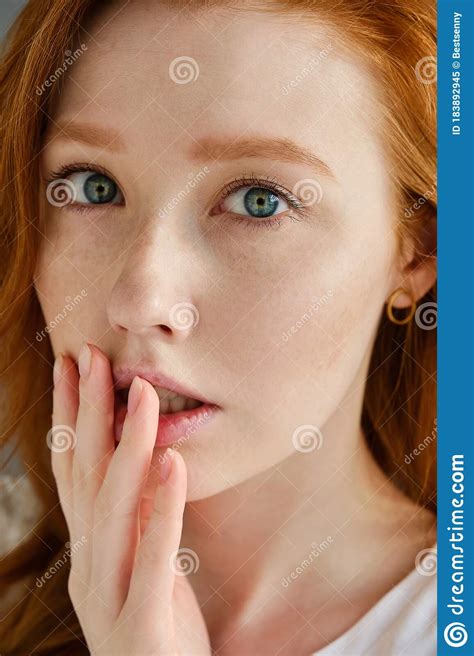 A Close Portrait Of A Beautiful Red Haired Girl With Blue Eyes Looks Into The Frame And