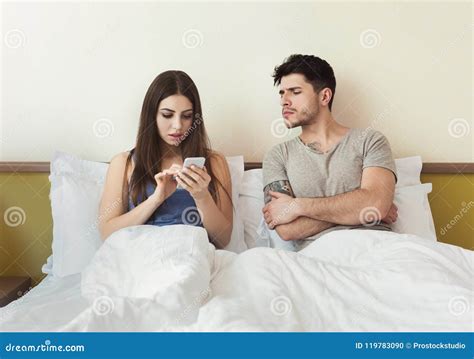 Jealous Husband Watching Wife Mobile Phone On The Bed Stock Photo