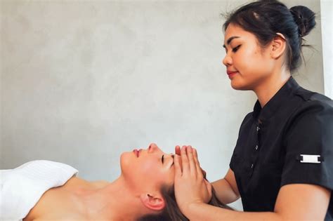 masajista asiática hace masaje de cabeza a mujer acostada en la habitación en la cama con