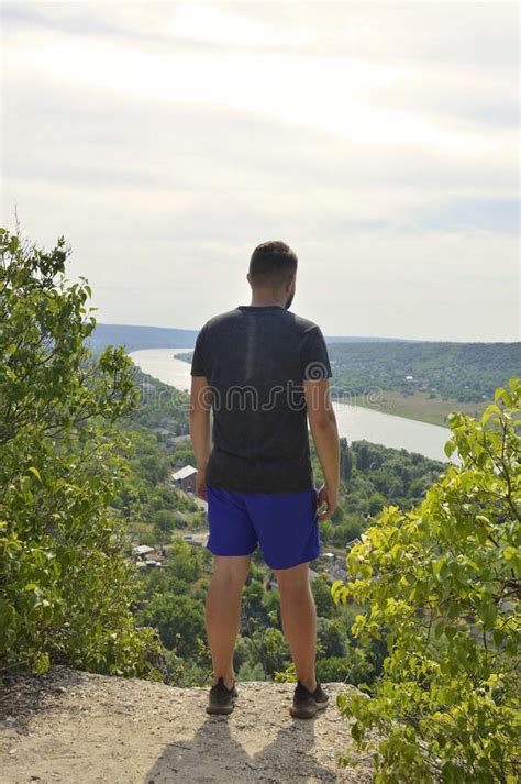 Young Tourist Man Stands On The Edge Of A Cliff In A Mountain Hike