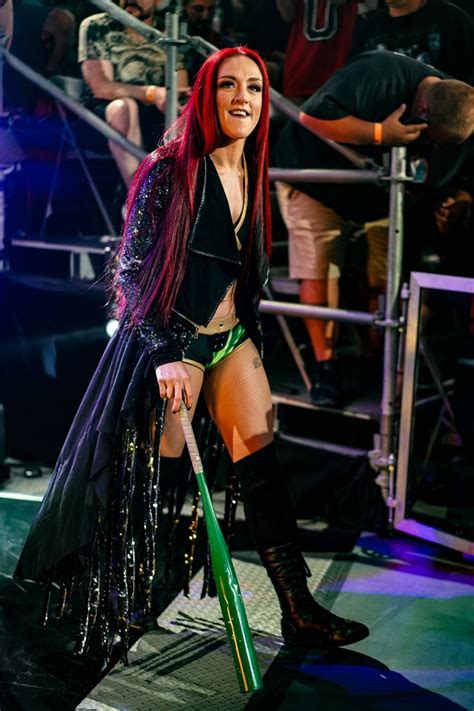 A Woman With Long Red Hair And Black Clothes On Stage Holding A Green