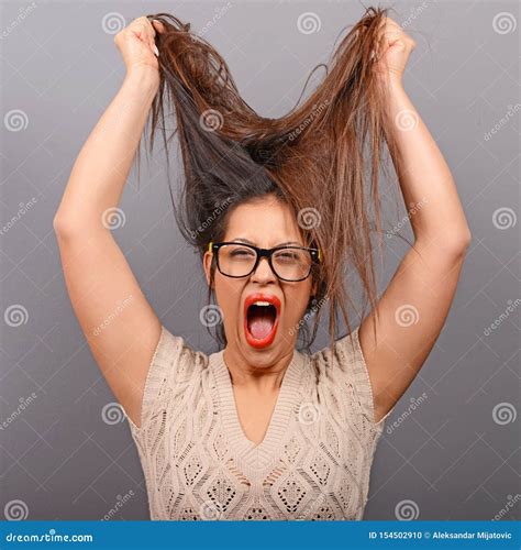 portrait of a hysterical woman pulling hair out against gray background stock image